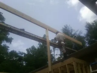 Carpenter setting a ridge beam over a new addition frame — Ice Dam Removal by Roofing Brothers in Glasco
