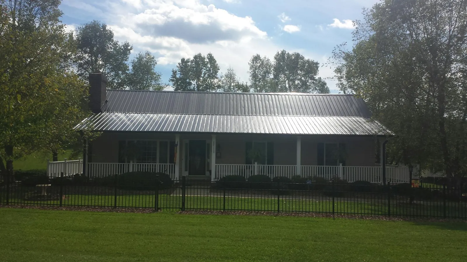 Gray metal roof on a brick ranch with a full width front porch — Gutter Guard Installation work by our crew in Glasco