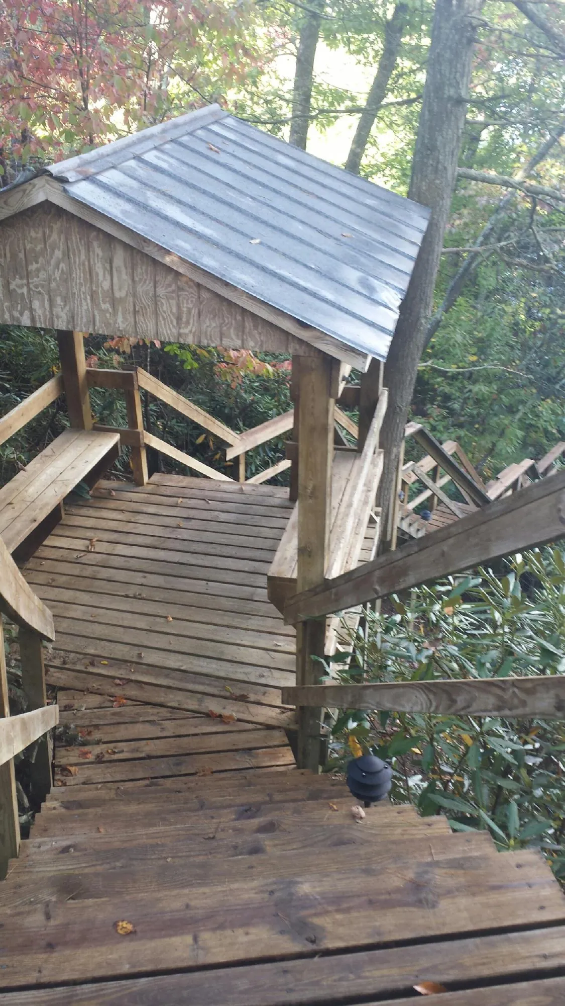 Metal roofed shelter over wooden steps on a wooded walkway — Skylight Repair & Installation work by our crew in Glasco