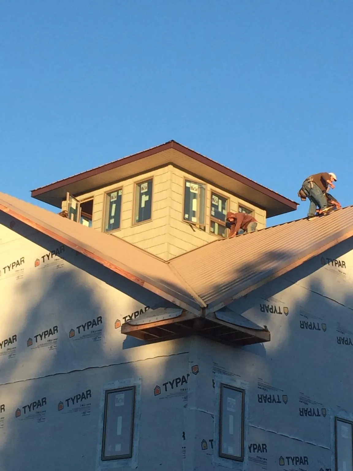 Roofers working around a rooftop cupola on a new metal roof at sunset — Roof Waterproofing in Glasco by Roofing Brothers